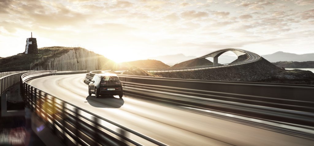 Car driving on a curving highway bridge at sunset