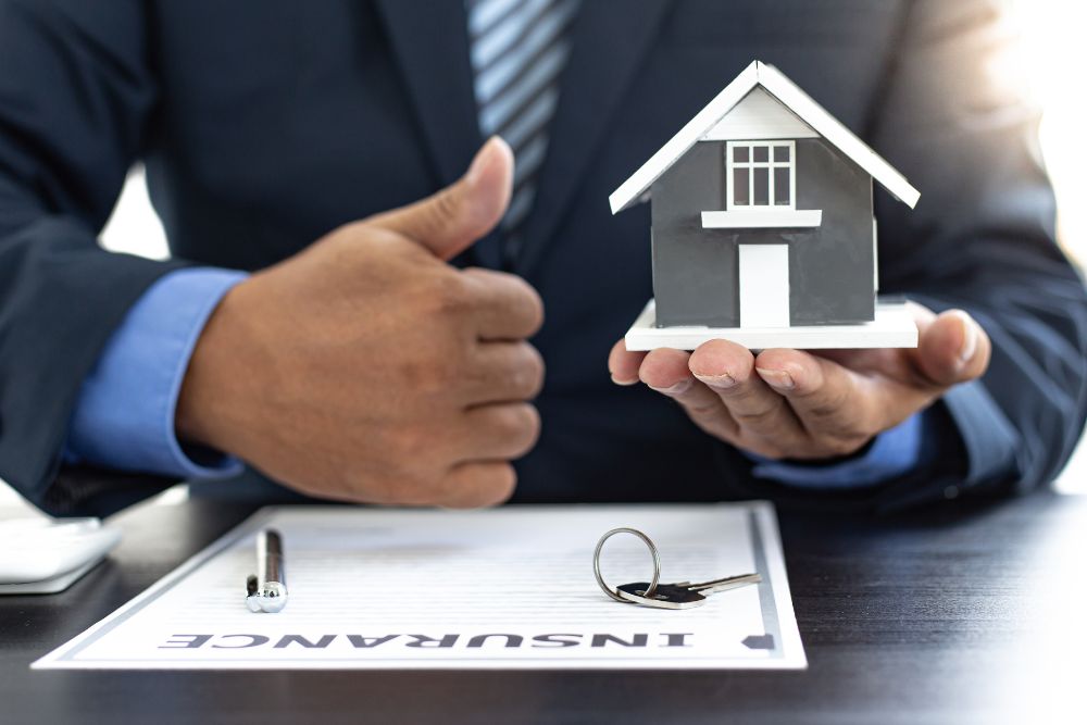 How Much is Homeowners Insurance on a $500,000 House? Insurance agent holding model home and policy paperwork for coverage comparison