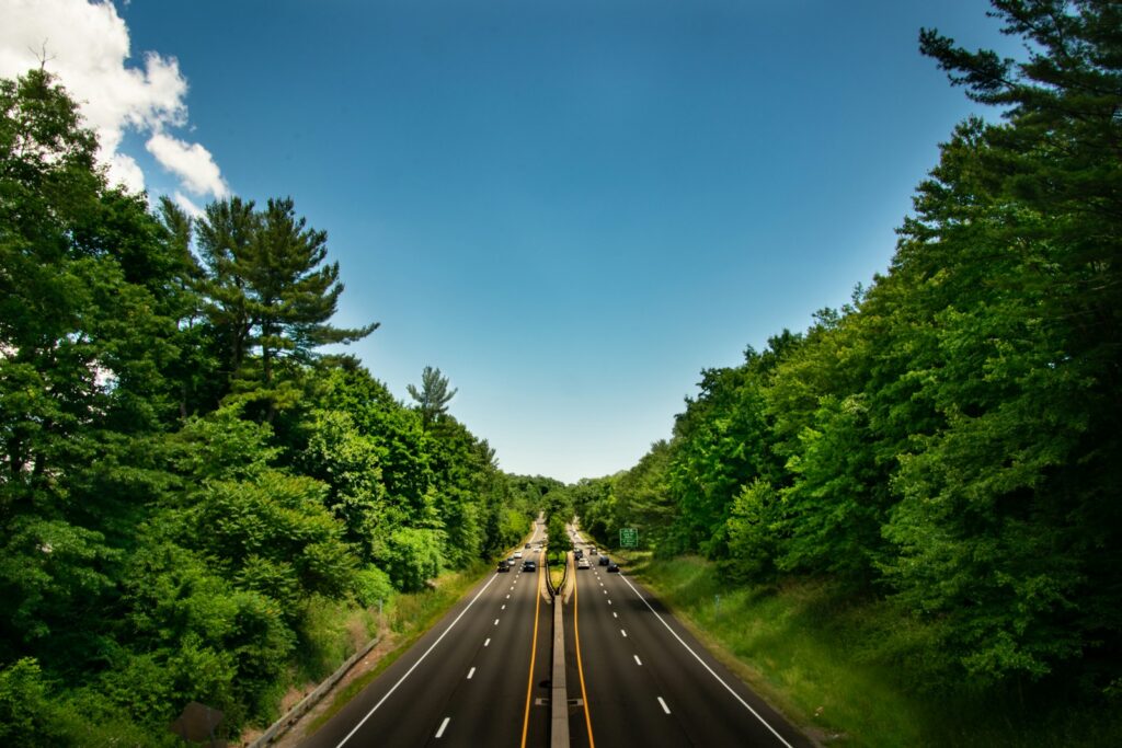 Divided highway winding through green woods in Connecticut on a clear summer day