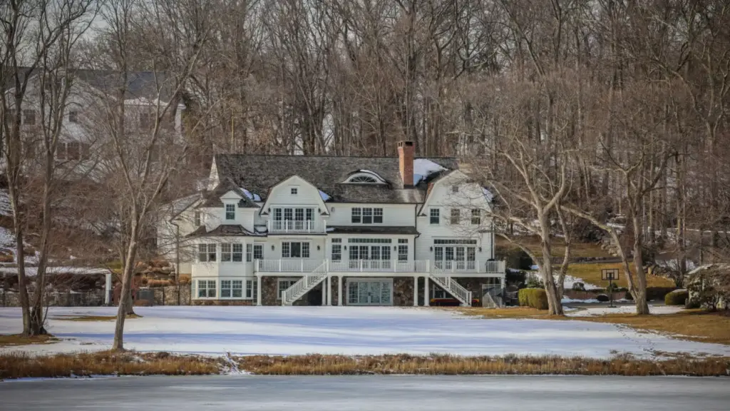 Large white waterfront estate home above a frozen pond in winter in Darien, Connecticut
