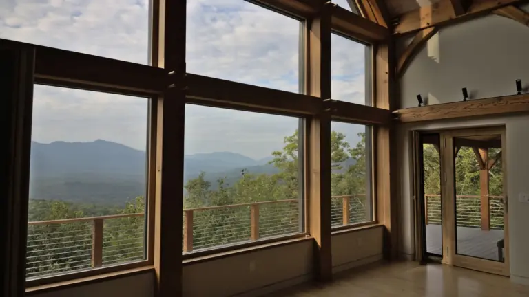 Timber-frame home interior with tall windows looking out at the mountains in Franconia, New Hampshire