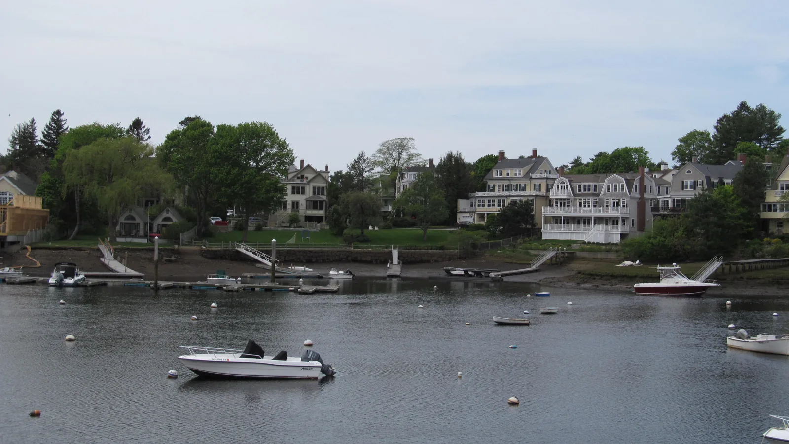 Waterfront homes and private docks along Manchester Harbor in Manchester-by-the-Sea, Massachusetts, with boats on moorings in the foreground