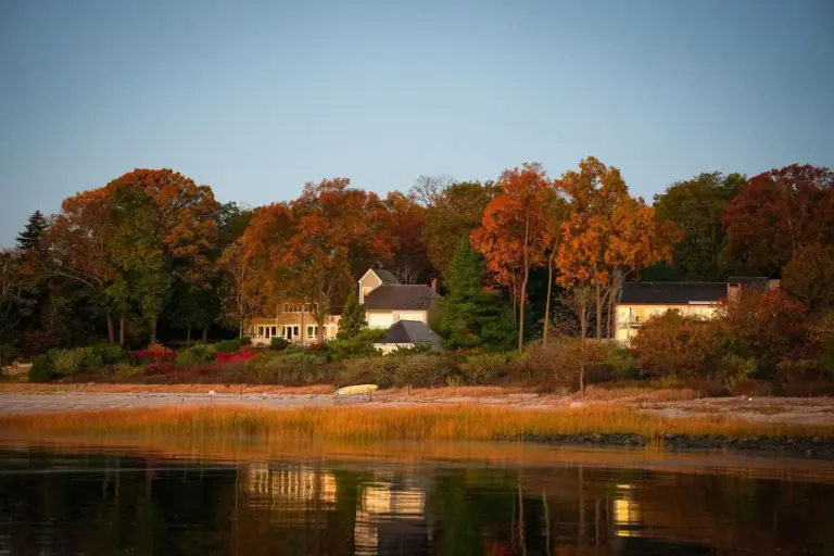 Waterfront homes among fall foliage behind a salt marsh on the Connecticut shoreline in Stamford at dawn