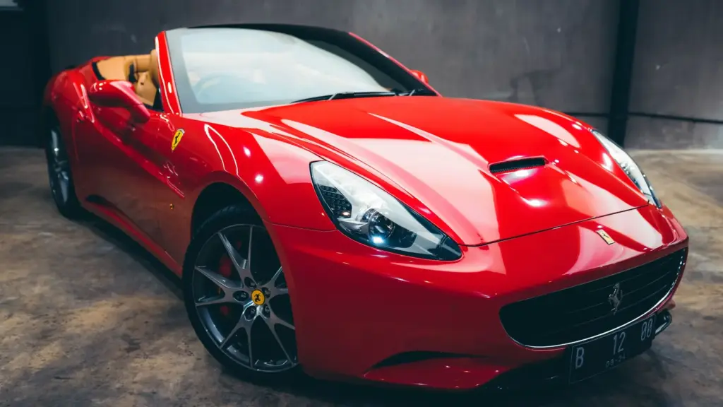 Red convertible sports car parked in a garage with concrete walls
